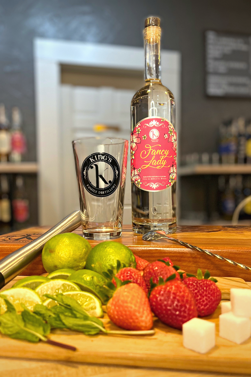 Fancy LAdy Rum bottle surrounded by limes, sugar cubes, and strawberries