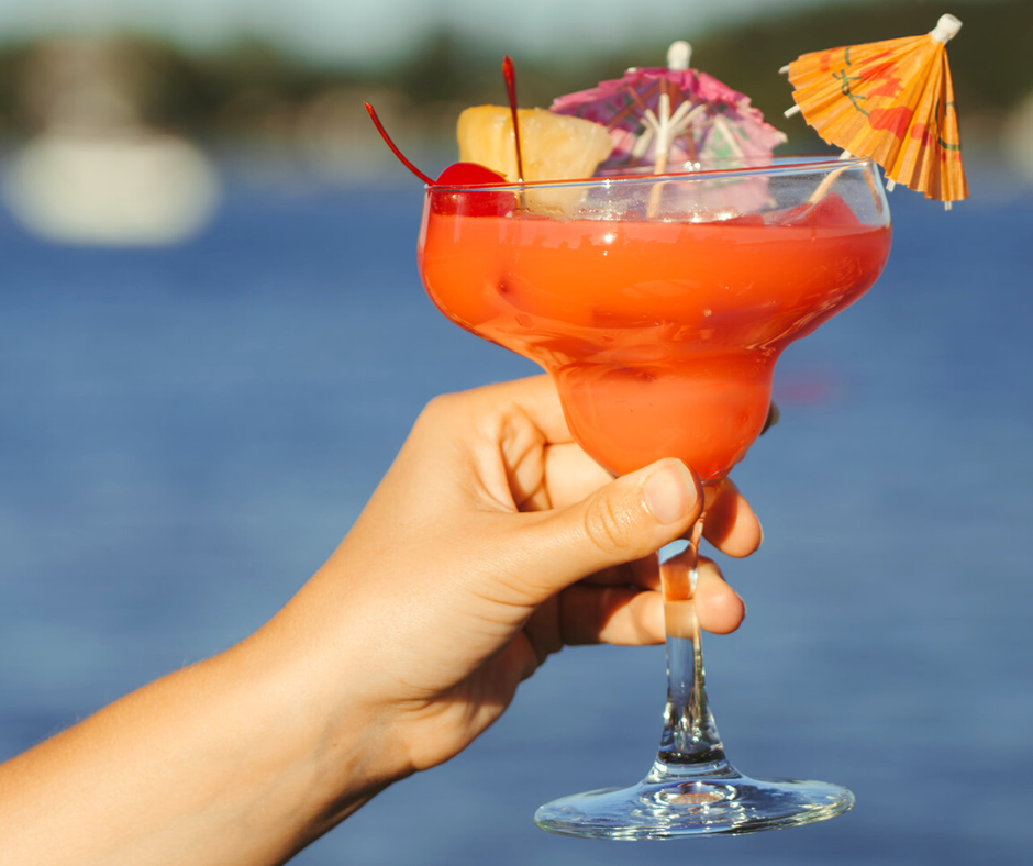 Pink tropical cocktail with paper umbrella and garnished with cherries and a pineapple 